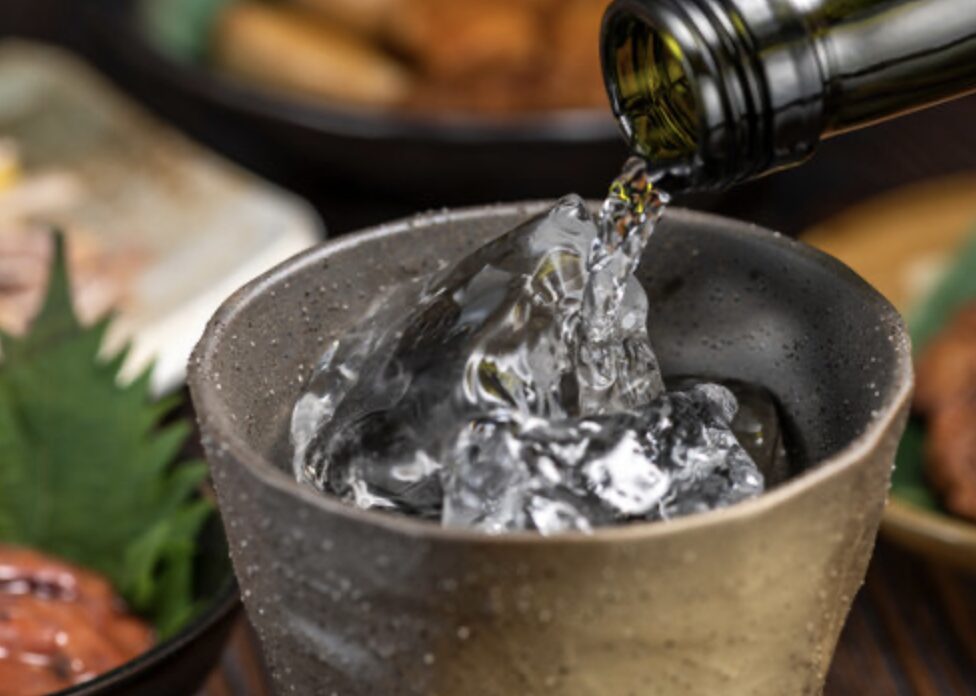 氷を入れた器に透明な焼酎を注ぐ冷酒のクローズアップ