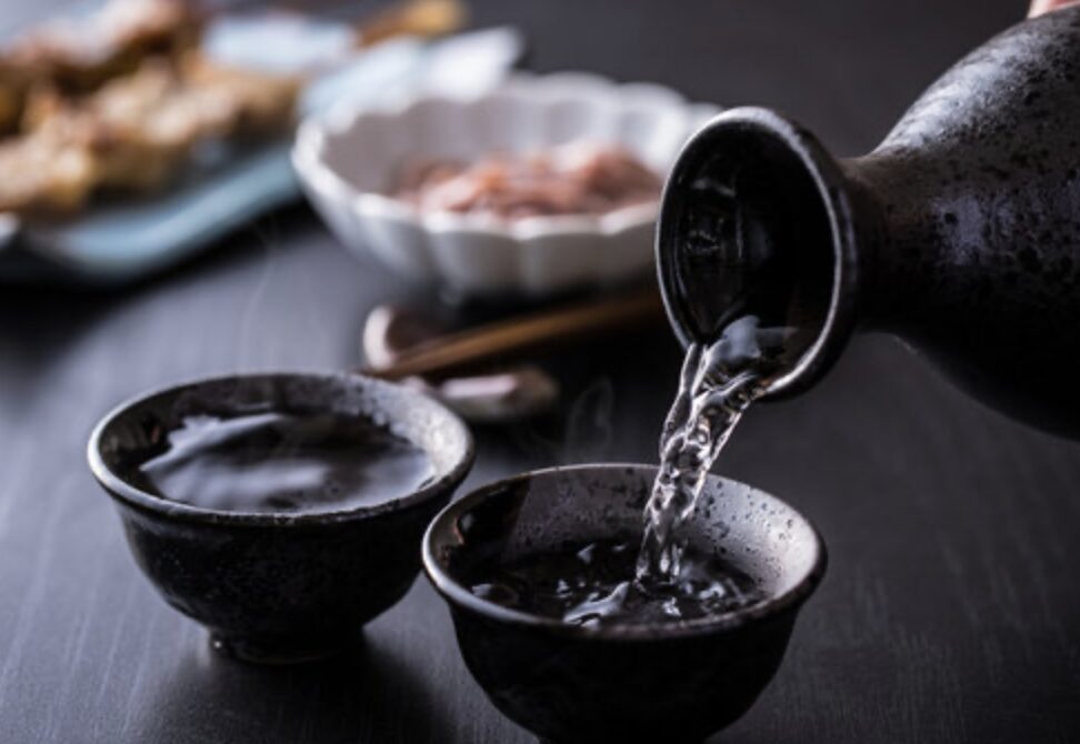 徳利から湯気の立つ日本酒をおちょこに注ぐ落ち着いた和の晩酌シーン